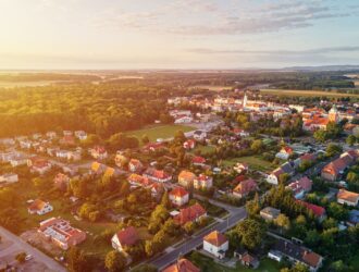 Widok z lotu ptaka na podmiejską dzielnicę, dzielnicę mieszkaniową z budynkami i ulicami w małym europejskim miasteczku o zachodzie słońca