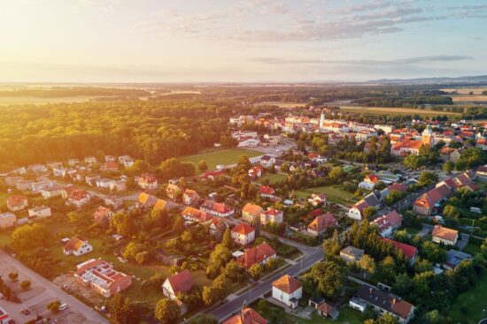 Widok z lotu ptaka na podmiejską dzielnicę, dzielnicę mieszkaniową z budynkami i ulicami w małym europejskim miasteczku o zachodzie słońca