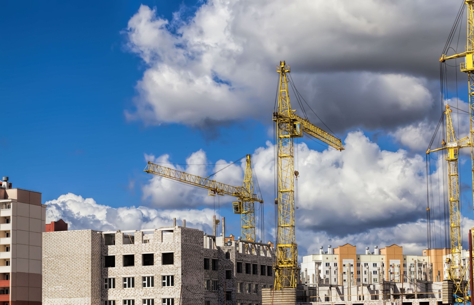 budowa nowego wielokondygnacyjnego budynku mieszkalnego z bloków żelbetowych, plac budowy, obszar działalności związanej z budową i remontem, duże dźwigi budowlane