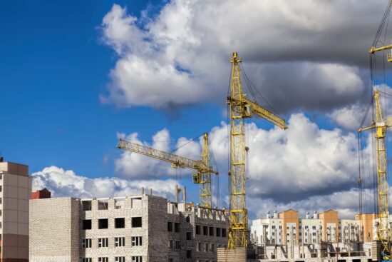 budowa nowego wielokondygnacyjnego budynku mieszkalnego z bloków żelbetowych, plac budowy, obszar działalności związanej z budową i remontem, duże dźwigi budowlane