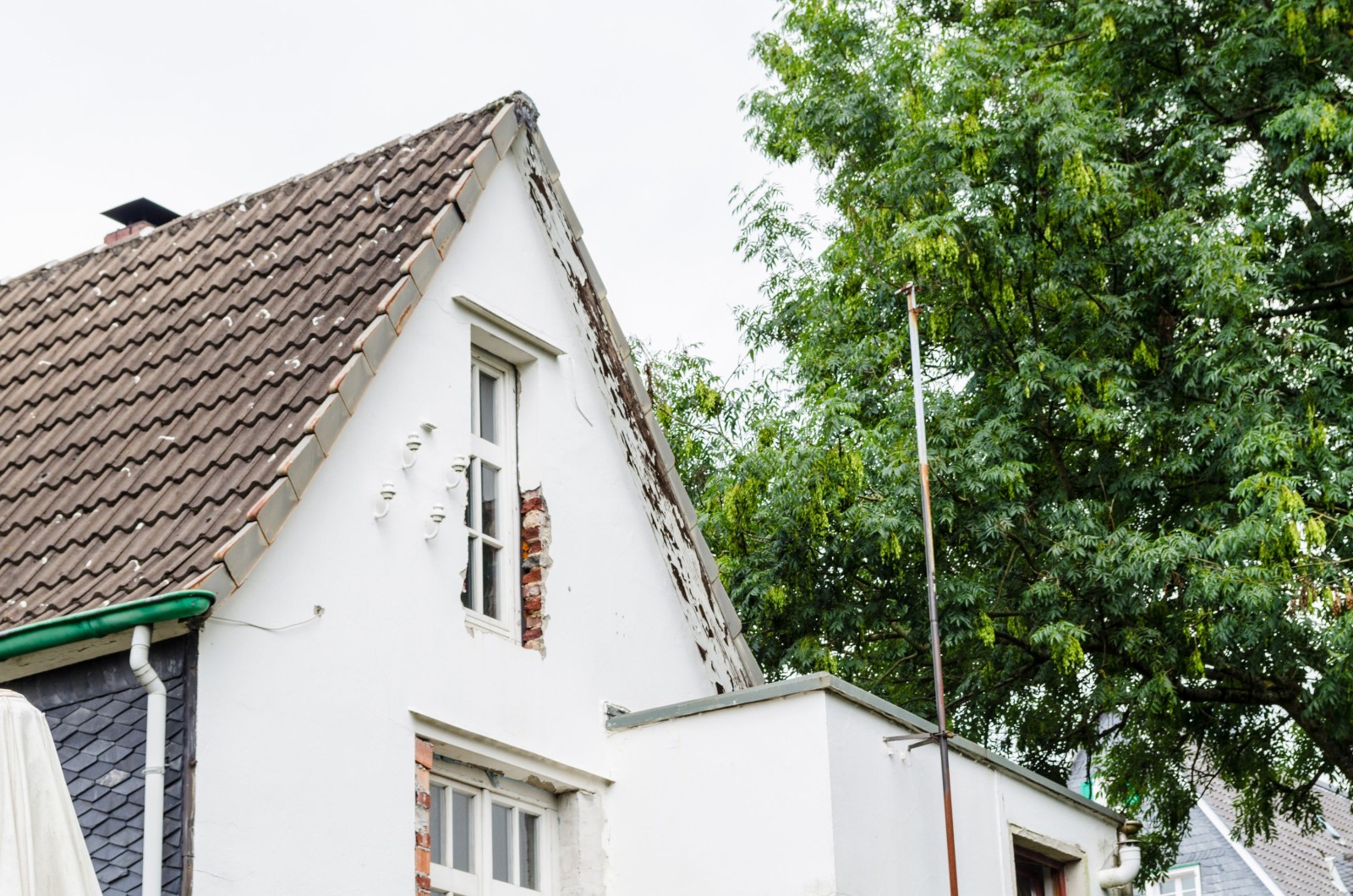 Widok fasady domu przeznaczonego do przebudowy. Nowe okna są już zamontowane.